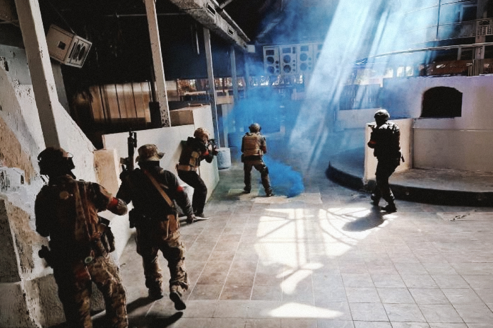 Jugadores con equipamiento táctico durante una partida de airsoft en un escenario interior de Valencia